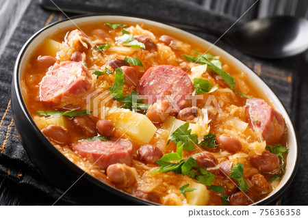 Thick sauerkraut soup with borlotti beans, potatoes and sausages close-up in a bowl. horizontal 75636358
