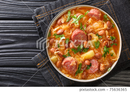 Sauerkraut stew with borlotti beans, potatoes and sausages close-up in a bowl. horizontal top view 75636365