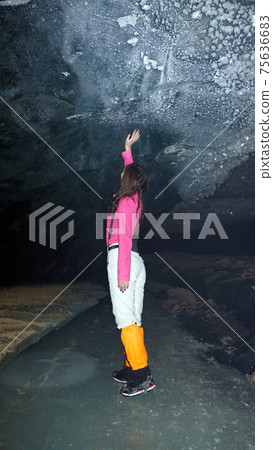 A girl poses inside an ice cave. A girl poses inside an ice cave. 75636683