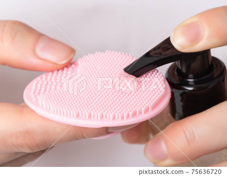A girl applies a scrub gel to a silicone facial brush. Facial skin care concept, macro, hygiene 75636720