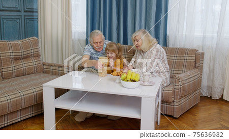 Excited child girl kid involved in build blocks board game with senior grandmother and grandfather Excited child girl kid involved in build blocks board game with senior grandmother and grandfather 75636982
