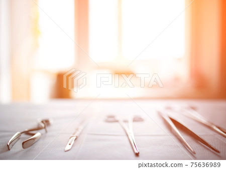 Surgical instruments on the table in the operating room of the hospital. Sunny sunset in the window. Surgery concept, amputation, complications after surgery. Copy space for text Surgical instruments on the table in the operating room of the hospital. Sunny sunset in the window. Surgery concept, amputation, complications after surgery. Copy space for text 75636989