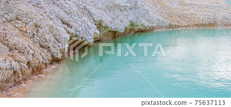 Shore with white clay close-up, turquoise azure water in pond, shallow lake with clear blue water. 75637113