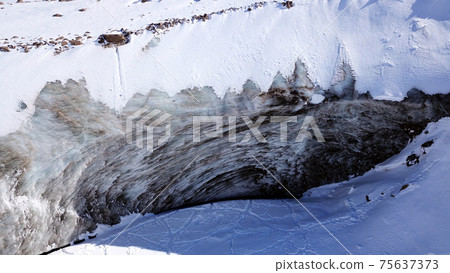 A huge wall of ice. Glacier in the mountains. 75637373