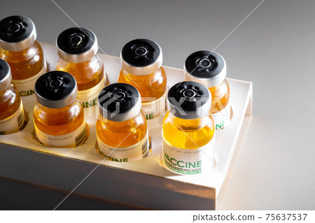 Vials with coronavirus vaccine in packaging on a black background and illuminated by a beam of light. Population vaccination recipe, vaccine research, SARS-Cov-2 Vials with coronavirus vaccine in packaging on a black background and illuminated by a beam of light. Population vaccination recipe, vaccine research, SARS-Cov-2 75637537