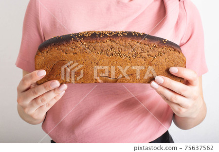 A girl holds black bread with coriander in her hands, close-up. The concept of the benefits and harms of black wheat bread, calorie content and health 75637562