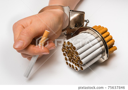 Female hand with handcuffs and cigarettes on white Female hand with handcuffs and cigarettes on white 75637846