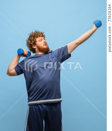 Funny red-headed man in blue sports uniform isolated on blue background 75638164