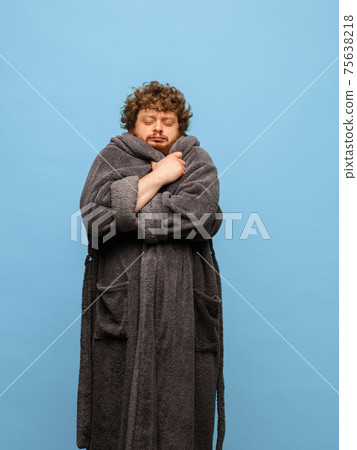 Caucasian man in bathrobe with cup of coffee isolated on blue background 75638218