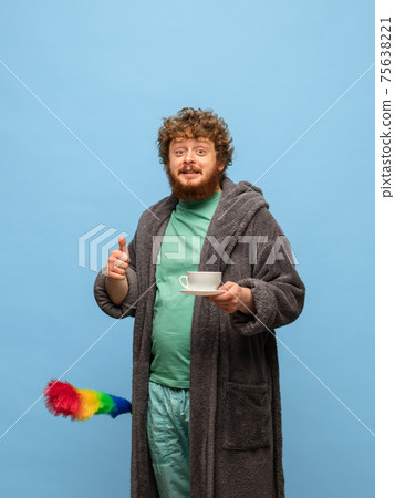 Red-headed man in bathrobe with cup of coffee isolated on blue background 75638221
