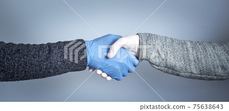 The concept of a safe handshake. Shaking hands in medical gloves on gray background. 75638643