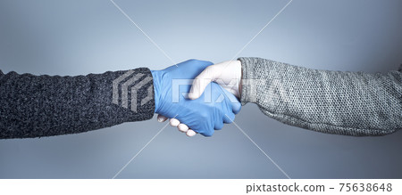 Shaking hands in medical gloves on a gray background. The concept of a safe handshake. Shaking hands in medical gloves on a gray background. The concept of a safe handshake. 75638648