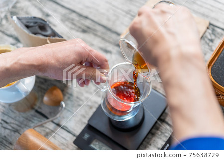 Coffee color lit up double wall glass poured into a coffee cup from a coffee drip server 75638729