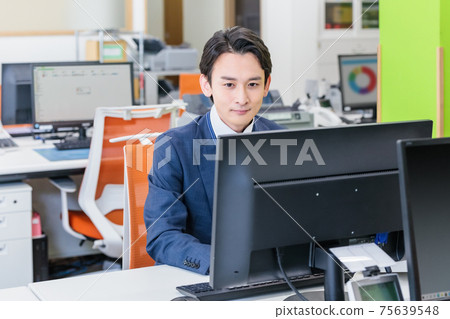 通過在辦公室看電腦屏幕工作的商人 通過在辦公室看電腦屏幕工作的商人 75639548