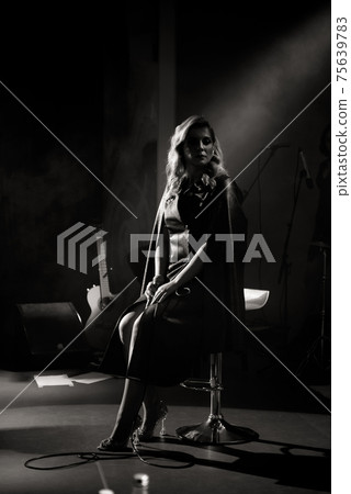 Singer with microphone on the stage in stage lighting Singer with microphone on the stage in stage lighting 75639783