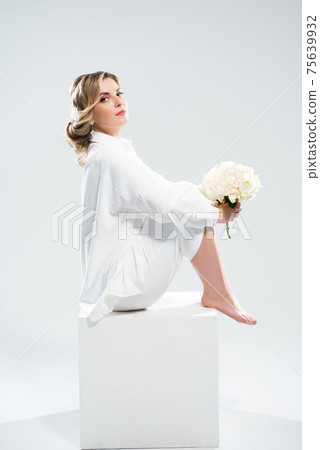 Beautiful young woman with clean fresh skin on face holding a bouquet of white flowers. Beautiful young woman with clean fresh skin on face holding a bouquet of white flowers. 75639932