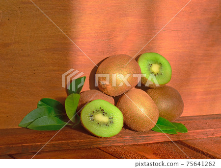 Kiwi on brown wooden background Kiwi on brown wooden background 75641262