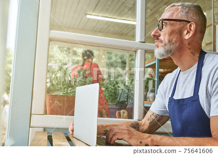 Middle aged caucasian businessman sitting at computer table Middle aged caucasian businessman sitting at computer table 75641606