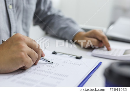 Businessman analyzing investment charts and pressing calculator buttons over documents. Accounting Concept. Businessman analyzing investment charts and pressing calculator buttons over documents. Accounting Concept. 75641983