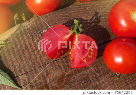 Tomato with slice on rustic wooden background. Fresh cut tomato on wooden table Tomato with slice on rustic wooden background. Fresh cut tomato on wooden table 75642295