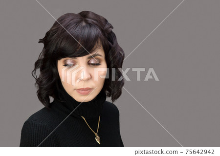 Portrait of sad adult woman in black clothes on gray background Portrait of sad adult woman in black clothes on gray background 75642942