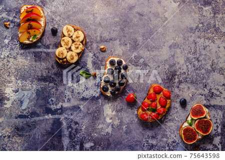 Homemade summer toast with cream cheese, nut butter and fruits and berries. 75643598