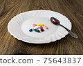 A bunch of pills on a plate 75643837