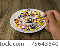 A bunch of pills on a plate 75643840
