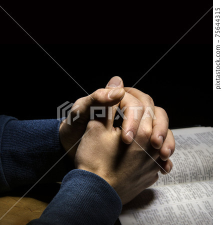 Hands folded in prayer over Scriptures Hands folded in prayer over Scriptures 75644315