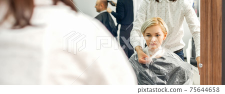 Hairdresser puts on transparent cape 75644658
