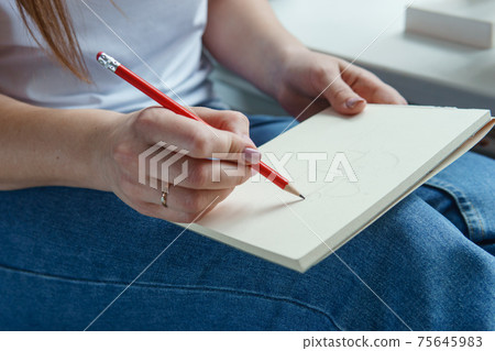 A pencil in a woman's hands. Drawing on a sheet of paper with a simple pencil. The concept of creativity and drawing. A pencil in a woman's hands. Drawing on a sheet of paper with a simple pencil. The concept of creativity and drawing. 75645983