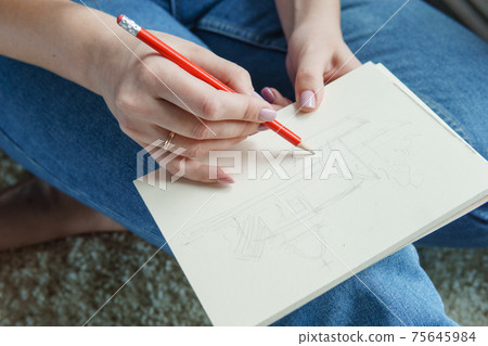 A pencil in a woman's hands. Drawing on a sheet of paper with a simple pencil. The concept of creativity and drawing. A pencil in a woman's hands. Drawing on a sheet of paper with a simple pencil. The concept of creativity and drawing. 75645984