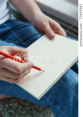 A pencil in a woman's hands. Drawing on a sheet of paper with a simple pencil. The concept of creativity and drawing. A pencil in a woman's hands. Drawing on a sheet of paper with a simple pencil. The concept of creativity and drawing. 75645985