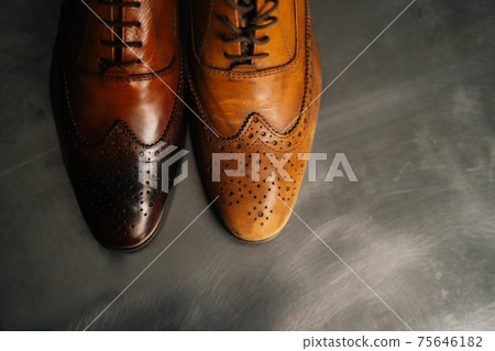 Close-up top view of old light brown leather shoe and repaired shiny shoes after restoration working. Close-up top view of old light brown leather shoe and repaired shiny shoes after restoration working. 75646182