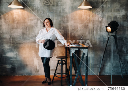 A businesswoman in a white shirt and pants stands in her office A businesswoman in a white shirt and pants stands in her office 75646380
