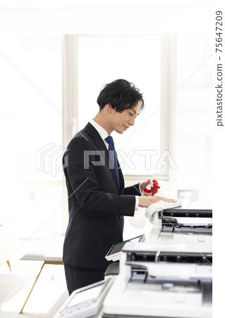 A man who disinfects and cleans a copier (multifunction machine) shared by the company 75647209