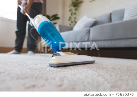 Close up on vacuum cleaner while woman cleaning the carpet in the living room. Asian woman doing chores at home. Close up on vacuum cleaner while woman cleaning the carpet in the living room. Asian woman doing chores at home. 75650376