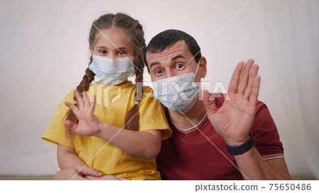 happy family face wearing medical a protective mask. pdad and daughter talking on video chat. coronavirus quarantine concept. people talking on video chat wearing protective medical protection mask 75650486