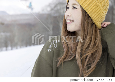 A young woman looking up at a ski resort, a snowboard image 75650933
