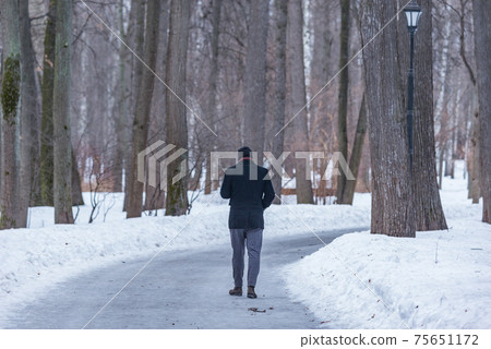 Young man walks in the city park at early spring time. Young man walks in the city park at early spring time. 75651172
