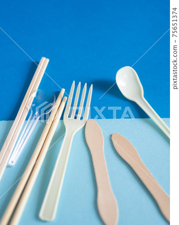 一次性筷子,湯匙和叉子在藍色的背景 一次性筷子,湯匙和叉子在藍色的背景 75651374