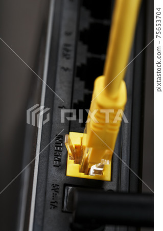 A yellow patch cord is inserted into the Wi-Fi port of the router to access the Internet. 75653704