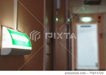 Green arrow for evacuation direction illuminated indoors. Green arrow for evacuation direction illuminated indoors. 75653720