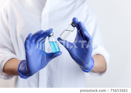 Two vaccine bottles in female doctor hands in protective gloves 75653881
