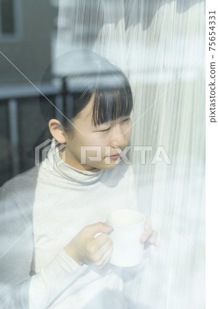 Girl drinking coffee by the window 75654331