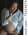From above Pregnant woman speaking on smartphone 75654879