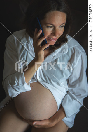 From above Pregnant woman speaking on smartphone 75654879