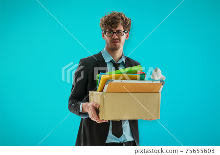Unemployed Business man worker carrying a packed box with upset expression for unemployment concept on blue background. Unemployed Business man worker carrying a packed box with upset expression for unemployment concept on blue background. 75655603