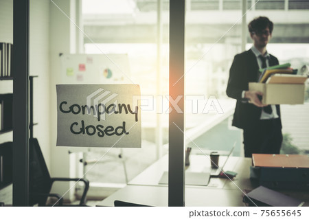 Company closed on windows of an empty office with business man packing beloning walking out of business by economic recession concept. 75655645