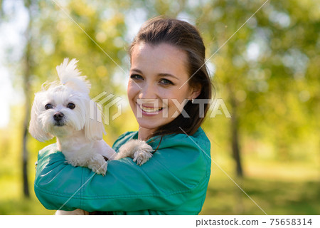 Young girl with her dog. Puppy white dog is running with it's owner. Concept about friendship, animal and freedom. Young girl with her dog. Puppy white dog is running with it's owner. Concept about friendship, animal and freedom. 75658314